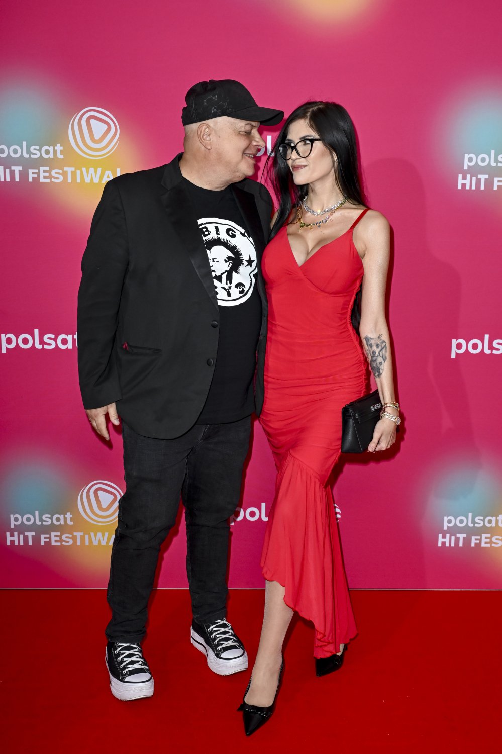 Krzysztof i Karolina Skibowienie szczędzą sobie czułości na ściance Sopot Festiwal, Karolina obrana w czerwoną suknię z dużym dekoltem, Krzysztof w czarnym garniturze, koszulke i czapkę z daszkiem