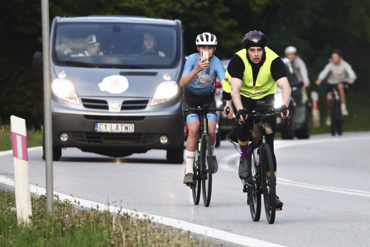 Łatwogang na rowerze, za nim sznurek jadącyh aut i rowerzystów