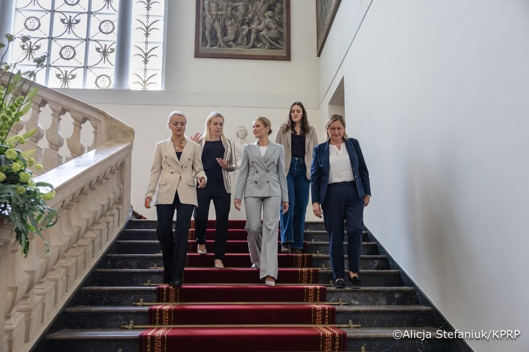 marta nawrocka ww szarym kostiumie idzie schodami