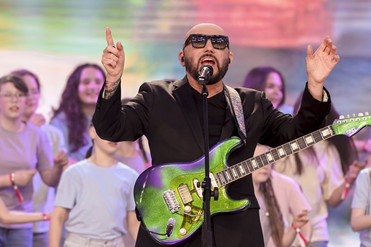 Grzegorz Skawiński śpiewa do mikrofonu na scenie