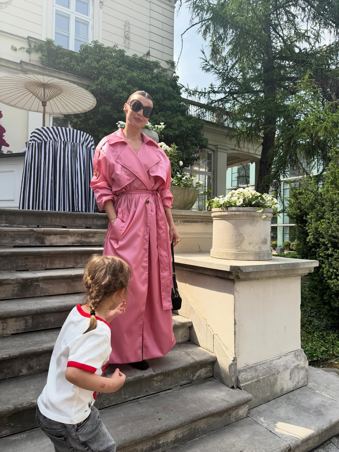 Katarzyna Sokołowska w różowej sukience stoi na schodach w towarzystwie synka