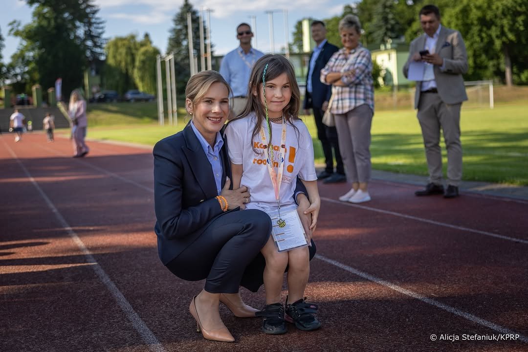 Marta Nawrocka przykucając obok kilkuletniej dziewczynki