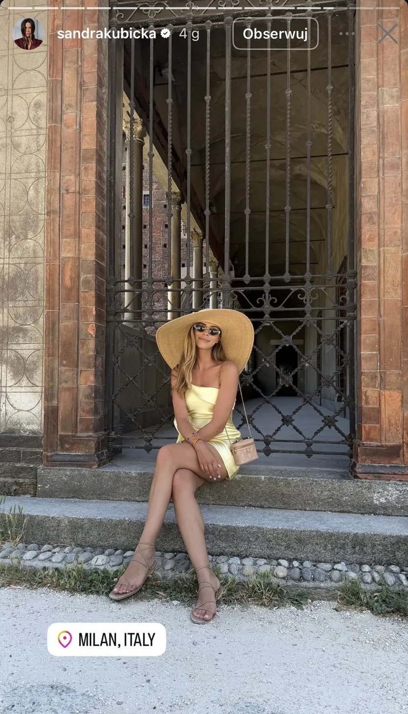 sandra kubicka w żółtej sukience i z wielkim kapeluszem na głowie sieedzi na schodach