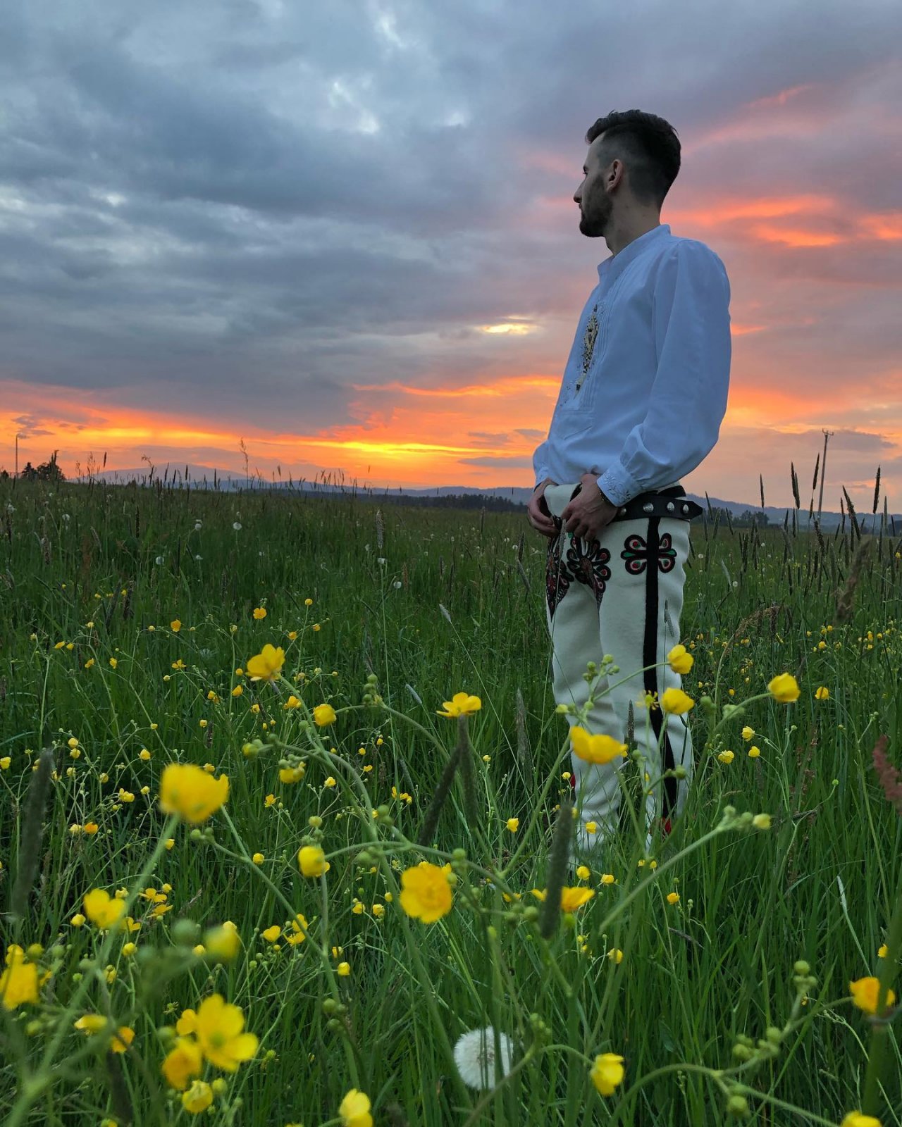 Grzegorz Miętus w góralskim stroju stoju na łące