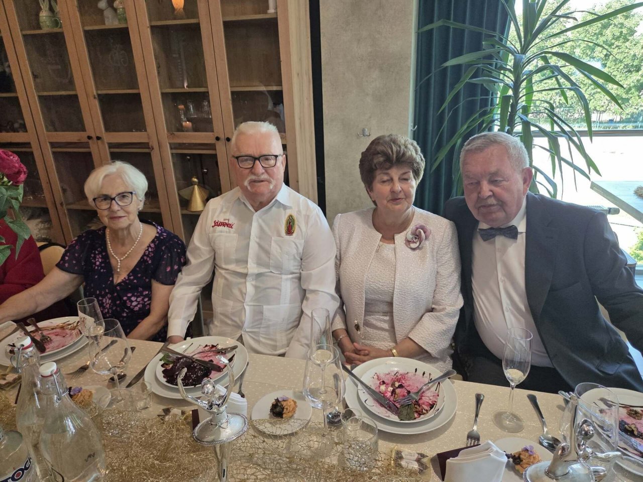 lech wałęsa z żoną i znajomymi siedzą za stołem