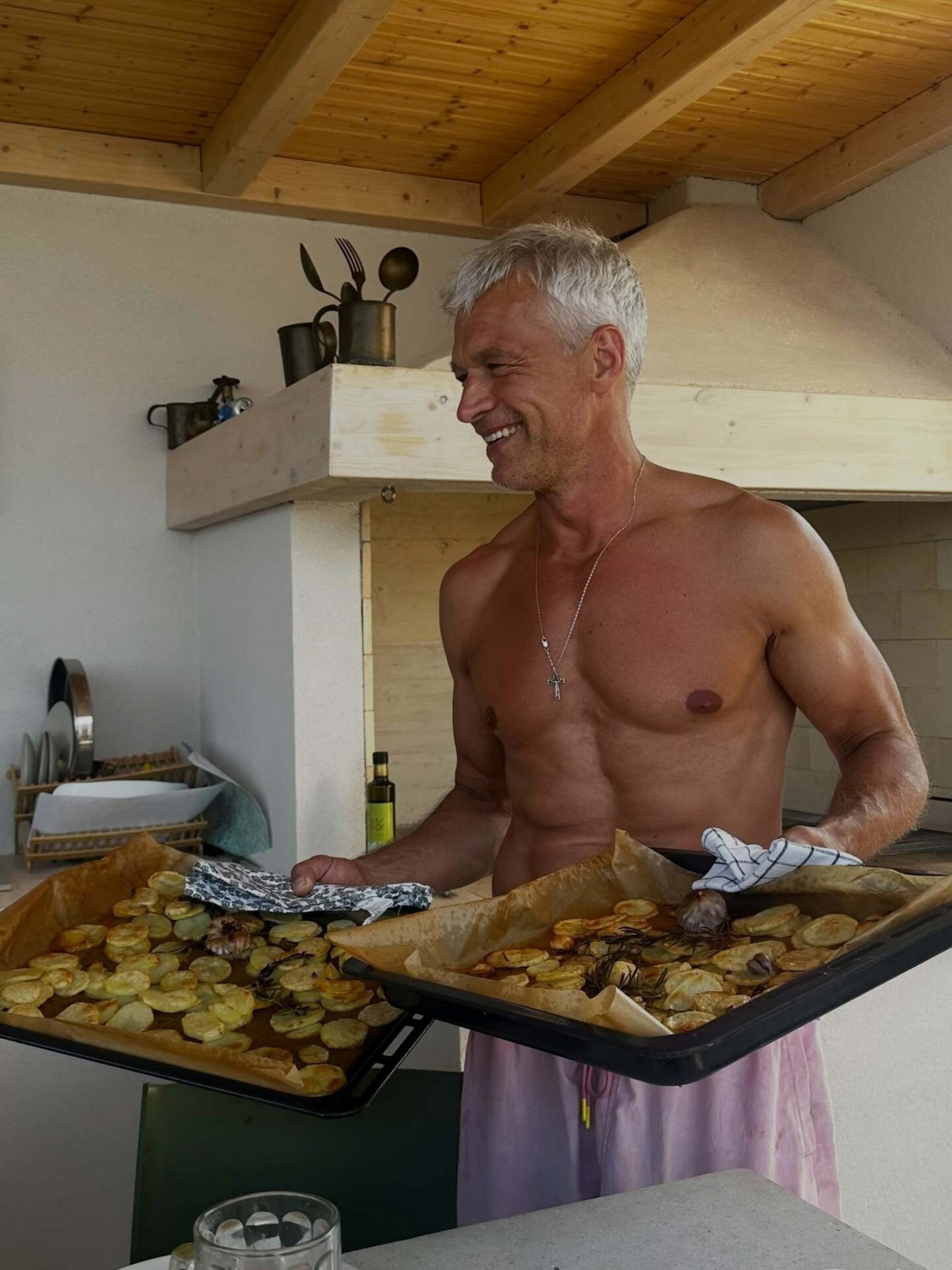 michał żebrowski bez koszulki trzyma blachę z jedzeniem