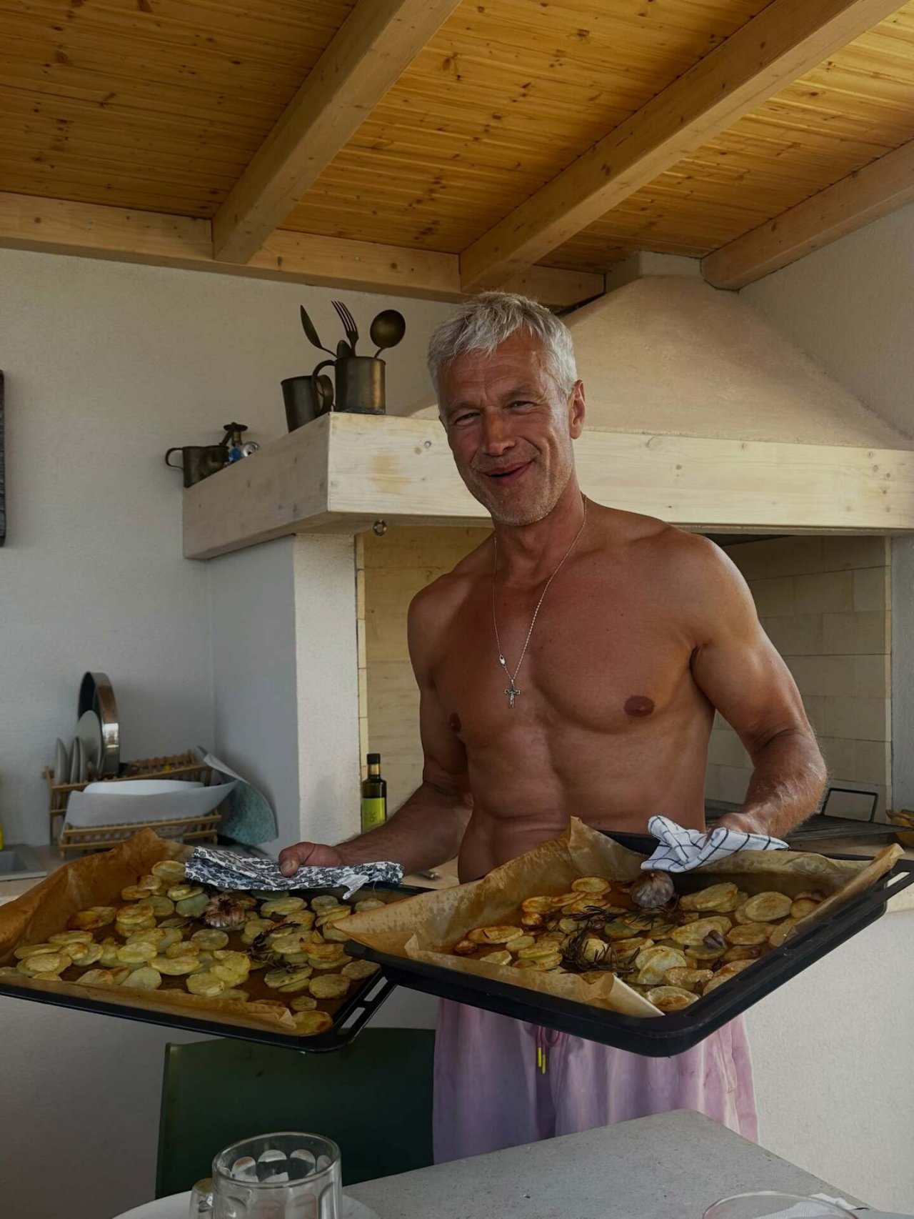 michał żebrowski bez koszulki trzyma blachę z jedzeniem