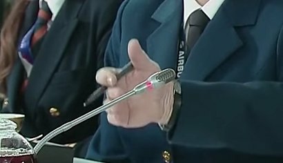 Na nagraniu widać, jak Putin macha ręką, a jego dłoń magicznie przenika przez stojący obok mikrofon.