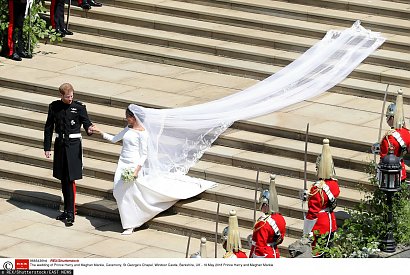 Prosta kreacja, której ozdobą był łódkowaty dekolt, była tłem dla urody Meghan Markle. Zdecydowanie wrażenie robił tren i welon, które ciągnęły się na kilka metrów. Jedynym strojnym elementem była tiara królowej Marii.