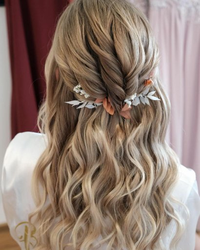 Piękna fryzura z lokowanych włosów z romantyczną, jesienną ozdobą.